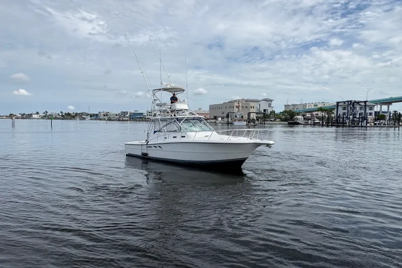 Slide: The Image of 2006 Rampage 38 Express boat on calm water near a marina under a cloudy sky. - 3