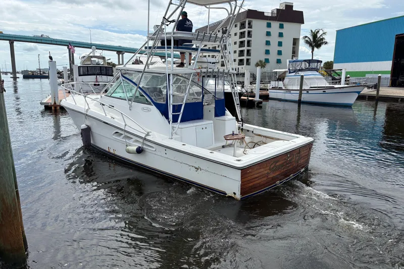 Slide: The Image of 2006 Rampage 38 Express boat docked in a marina, with a bridge and buildings nearby. - 4