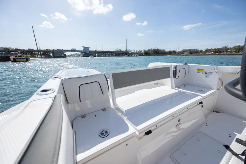 Slide: The Image of 2023 Yamaha Boats 255 FSH Sport E interior with seating, on a sunny day by the water. - 24