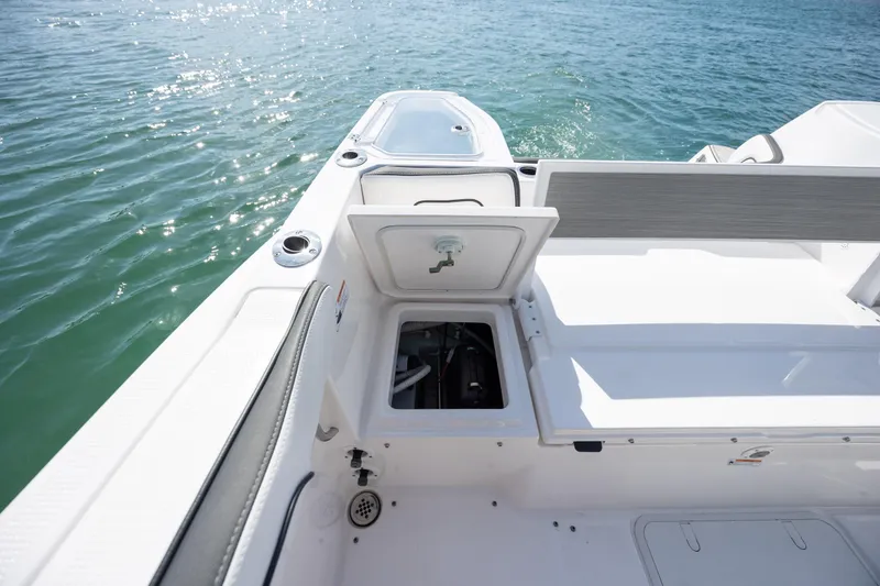 Slide: The Image of 2023 Yamaha Boats 255 FSH Sport E deck with open storage compartment, on calm water. - 35