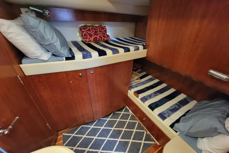 Slide: The Image of 2005 Tiara Yachts 4400 Sovran cabin with striped bedding and wooden interior. - 15