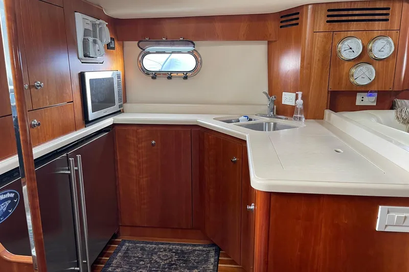 Slide: The Image of 2005 Tiara Yachts 4400 Sovran kitchen with wood cabinetry, microwave, and sink. - 18