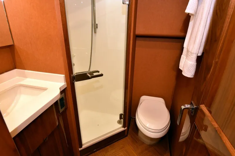 Slide: The Image of Bathroom interior of 2019 Viking 80 Sky Bridge yacht, featuring shower, toilet, and sink. - 36