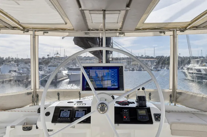 Slide: The Image of Cockpit view of 2022 Lagoon 52 F yacht with navigation display and marina backdrop. - 12