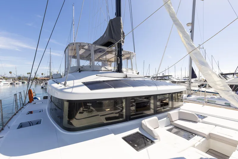 Slide: The Image of 2022 Lagoon 52 F catamaran docked at a marina under clear blue skies. - 13