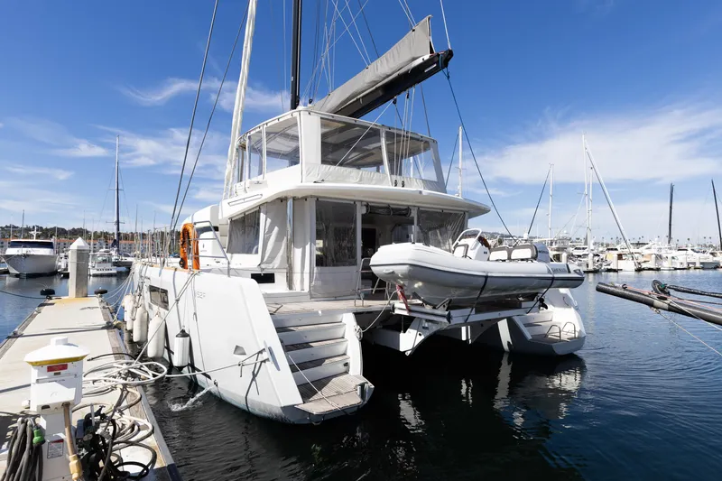 Slide: The Image of 2022 Lagoon 52 F catamaran docked at marina, featuring sleek design and tender boat. - 14