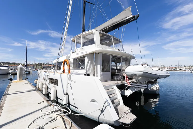 Slide: The Image of 2022 Lagoon 52 F catamaran docked at marina under clear blue sky. - 15