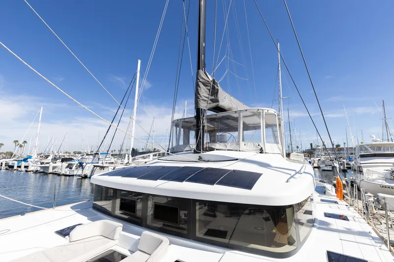 Slide: The Image of 2022 Lagoon 52 F catamaran docked in a marina under clear blue skies. - 16
