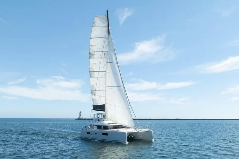 Slide: The Image of 2022 Lagoon 52 F catamaran sailing on open water with lighthouse in background. - 3