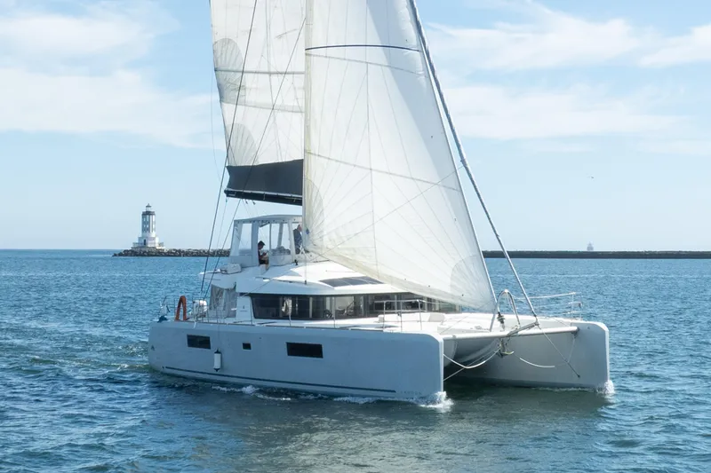 Slide: The Image of 2022 Lagoon 52 F catamaran sailing near a lighthouse on a sunny day. - 4