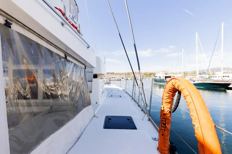 Slide: The Image of 2022 Lagoon 52 F yacht deck with marina view, featuring safety equipment. - 64