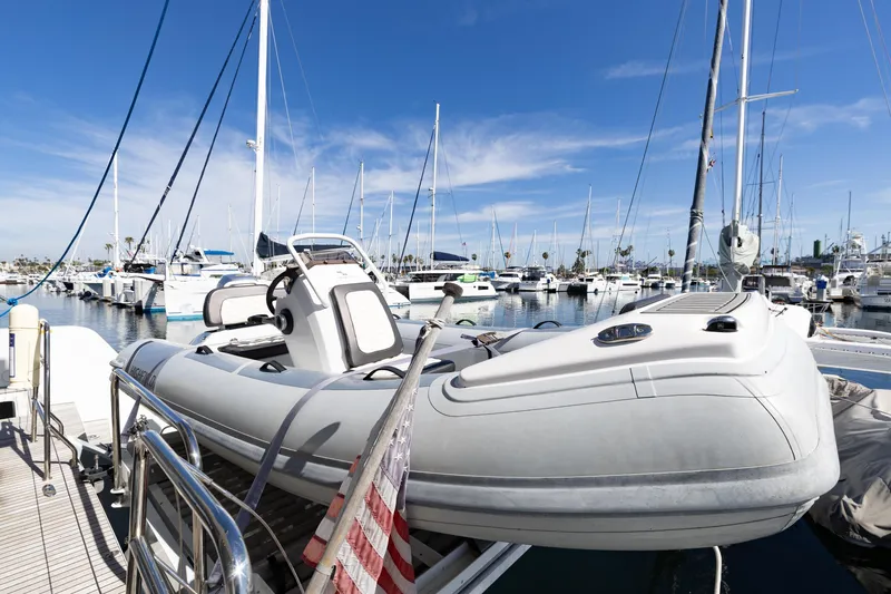 Slide: The Image of Docked Lagoon 52 F yacht, 2022 model, with inflatable boat, in a marina under clear skies. - 75
