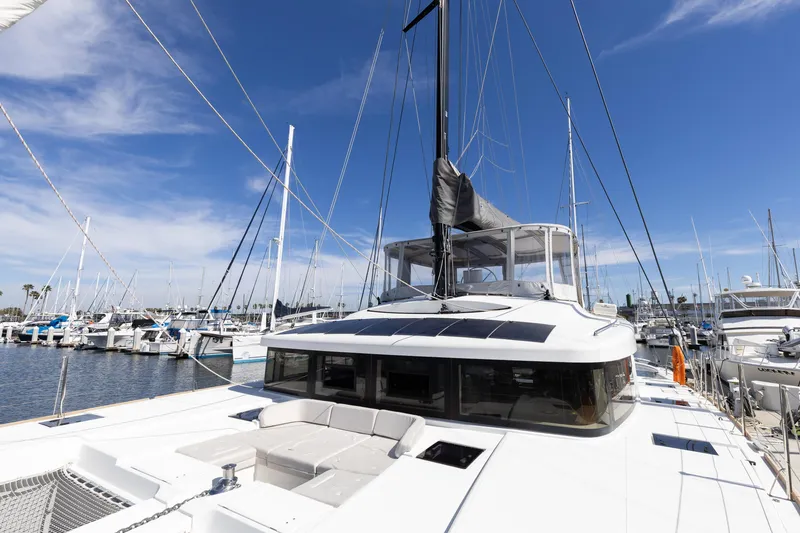 Slide: The Image of 2022 Lagoon 52 F catamaran docked at marina under clear blue sky. - 78