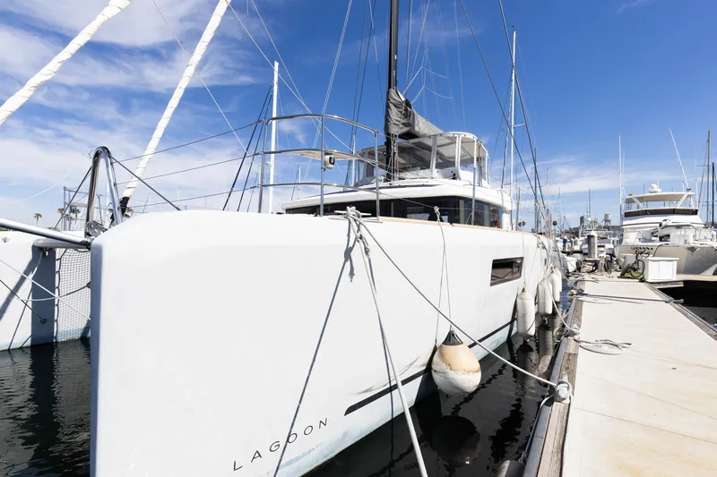 Slide: The Image of 2022 Lagoon 52 F catamaran docked at marina under clear blue sky. - 84