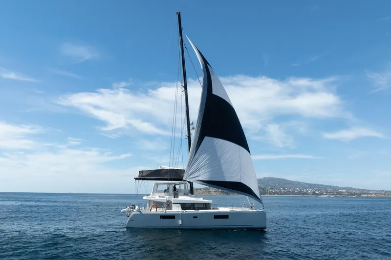 Slide: The Image of 2022 Lagoon 52 F catamaran sailing on open sea under clear blue sky. - 90