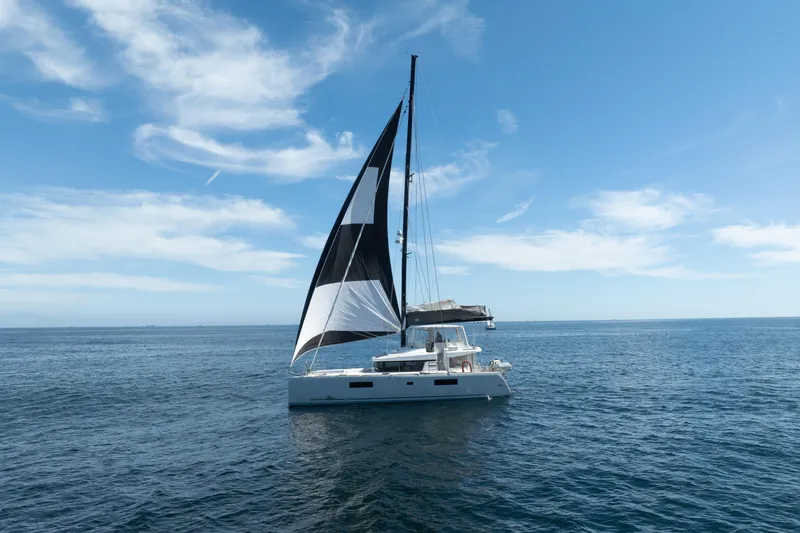 Slide: The Image of 2022 Lagoon 52 F catamaran sailing on open sea under clear blue sky. - 91