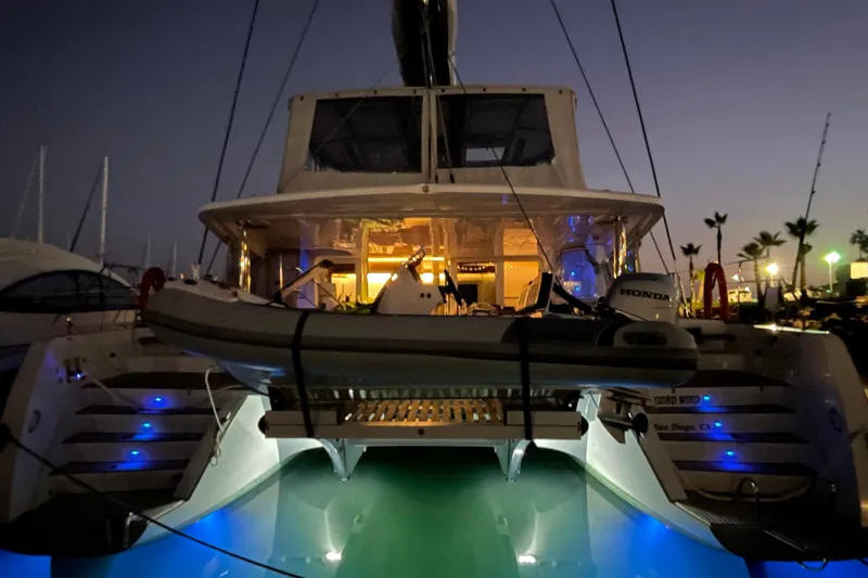 Slide: The Image of Lagoon 52 F 2022 catamaran illuminated at night in marina, featuring a small boat on deck. - 97