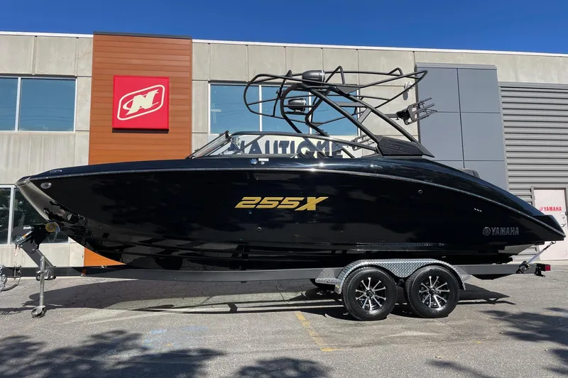 The Image of 2026 Yamaha Boats 255XD in black, displayed on a trailer outside a building. - 1