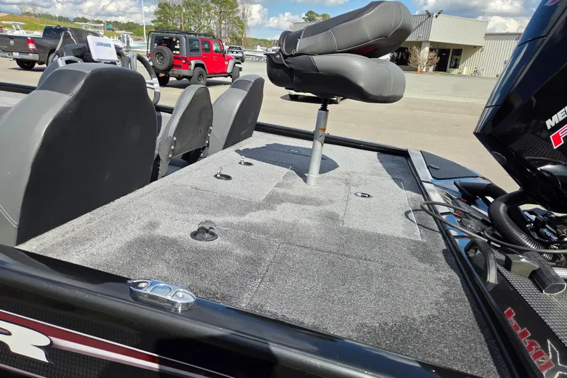 Slide: The Image of 2025 Tracker Savage 215 boat interior with seating and motor, parked outdoors. - 12