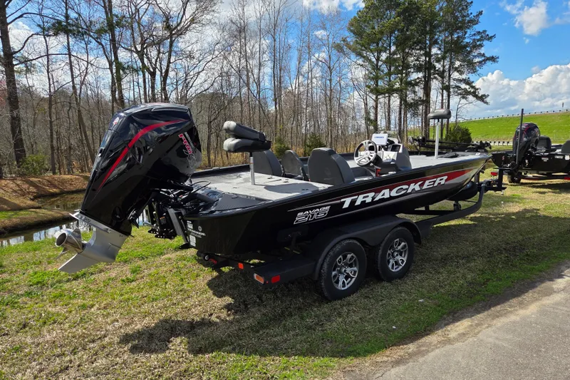 Slide: The Image of 2025 Tracker Savage 215 boat on trailer, parked outdoors near trees and grass. - 2