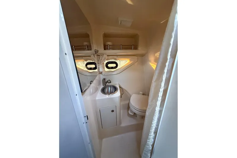 Slide: The Image of 2014 Sea Ray Sundancer 260 bathroom with sink, toilet, and portholes. - 8