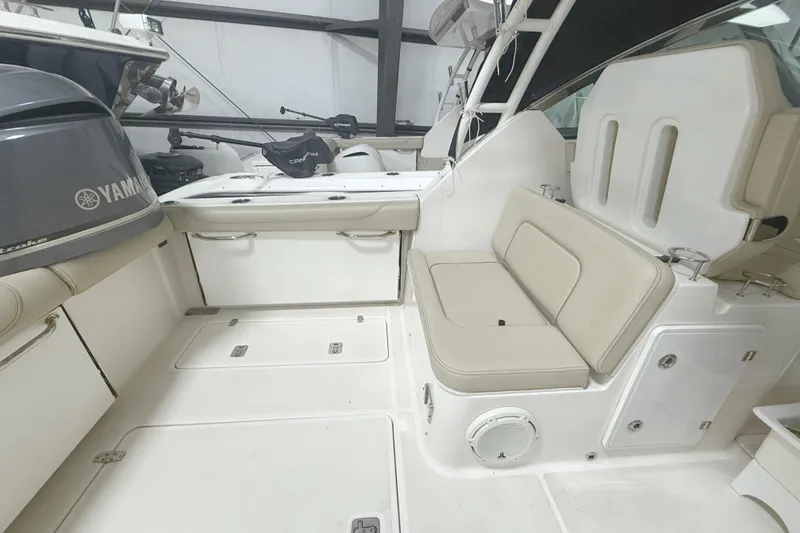 Slide: The Image of 2018 Pursuit DC 325 Dual Console boat interior with Yamaha engine, featuring beige seating and storage compartments. - 10