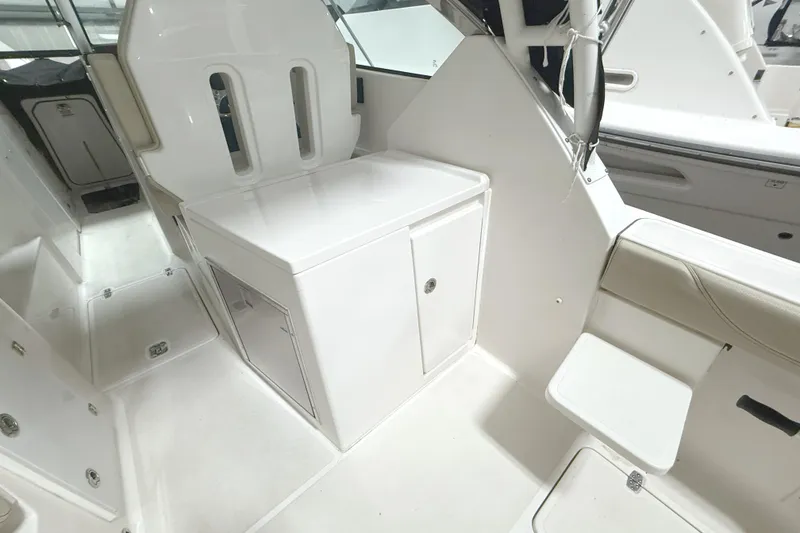Slide: The Image of 2018 Pursuit DC 325 Dual Console interior with white seating and storage compartments. - 17