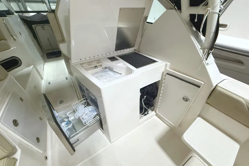 Slide: The Image of 2018 Pursuit DC 325 Dual Console interior with sink, storage, and seating. - 18