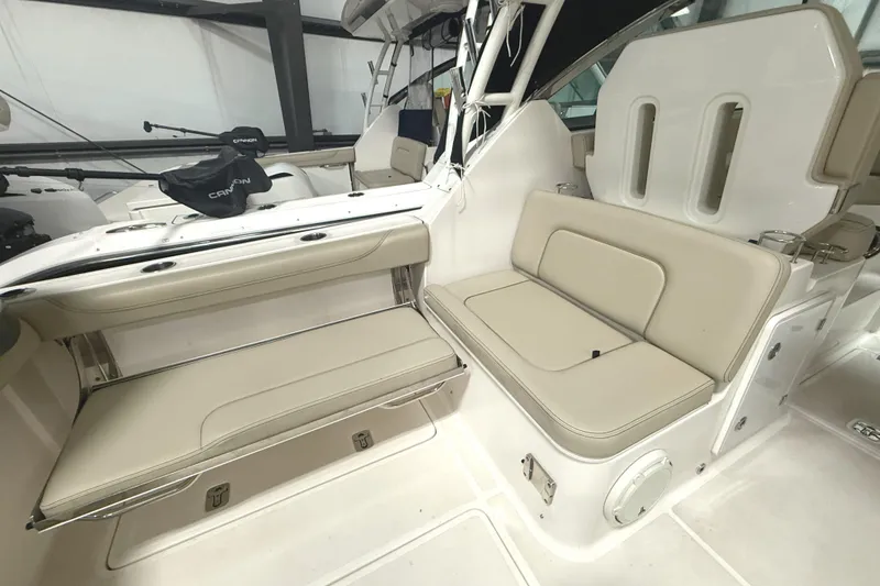 Slide: The Image of 2018 Pursuit DC 325 Dual Console boat interior with beige seating and storage compartments. - 19