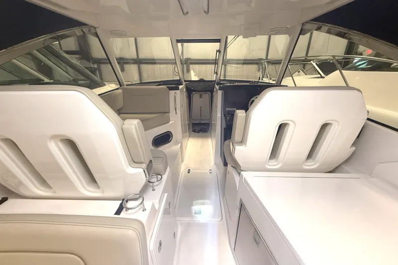 Slide: The Image of Interior of a 2018 Pursuit DC 325 Dual Console boat, featuring white seating and helm. - 21