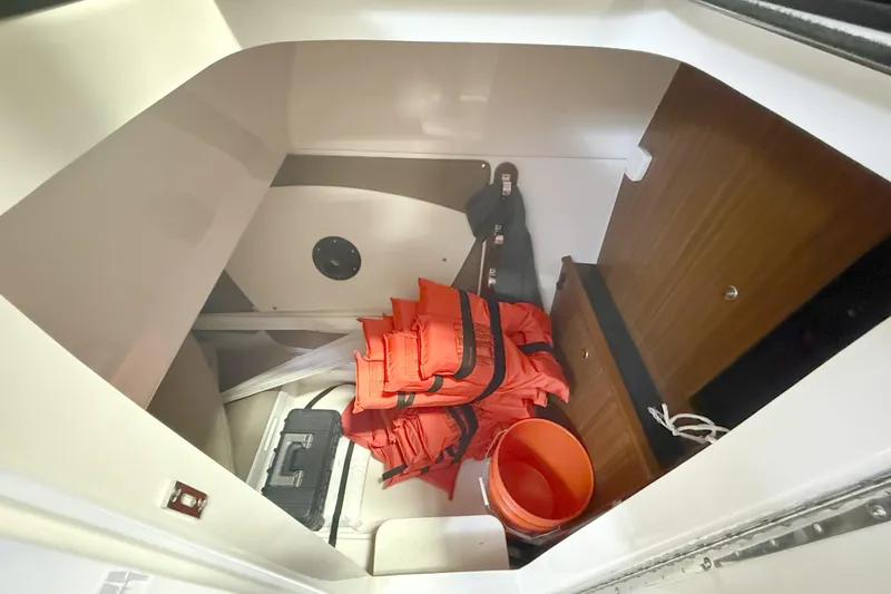 Slide: The Image of Storage compartment in a 2018 Pursuit DC 325 Dual Console with life jackets and equipment. - 26