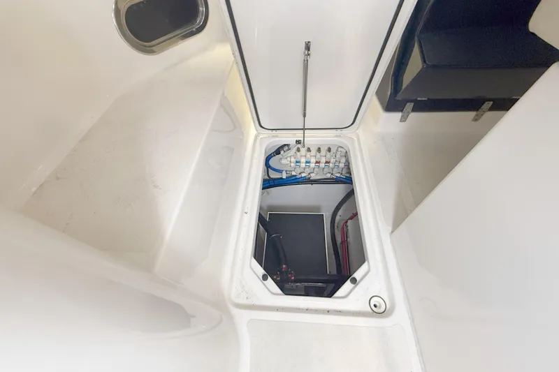 Slide: The Image of 2018 Pursuit DC 325 Dual Console storage compartment with visible wiring and plumbing. - 32