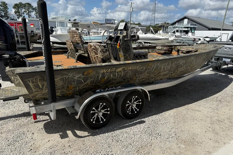 Slide: The Image of 2022 War Eagle 2170 Blackhawk boat on trailer, camo design, parked outdoors. - 12