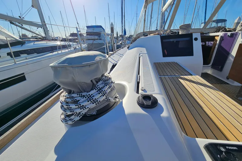 Slide: The Image of 2018 Dufour 460 Grand Large yacht deck with ropes and wooden seating in marina. - 2