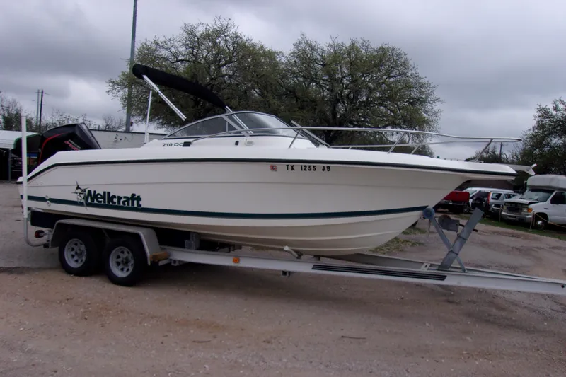The Image of 1998 Wellcraft 210 Sportsman boat on trailer, parked outdoors. - 1