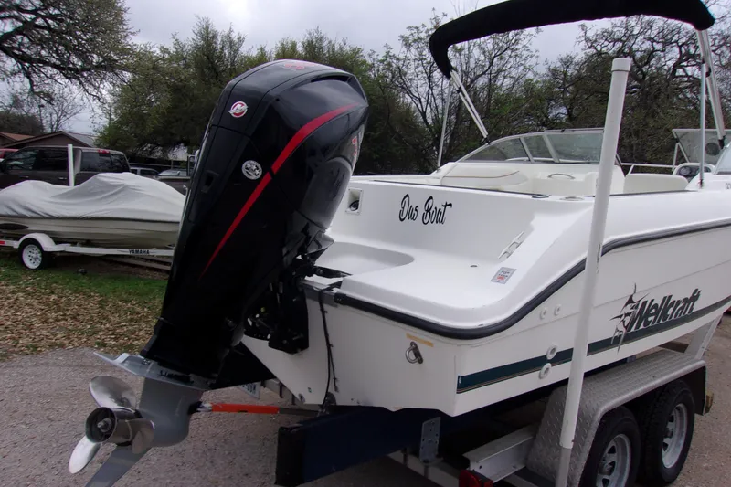 Slide: The Image of 1998 Wellcraft 210 Sportsman boat on trailer with outboard motor, parked outdoors. - 4