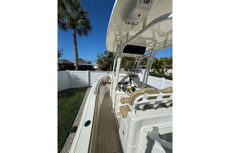 Slide: The Image of 2018 Key West 239 FS boat with beige seating, parked near a white fence and palm tree. - 4