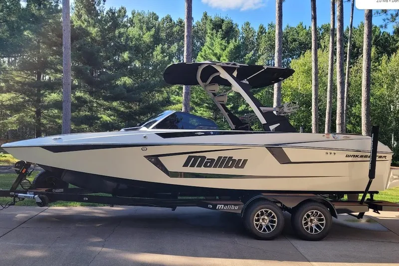 Slide: The Image of 2023 Malibu Wakesetter 23 MXZ boat on trailer, surrounded by trees. - 11