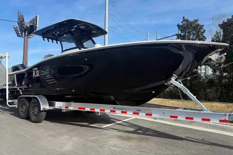 The Image of 2026 Scout 277 LXF boat on trailer, sleek black design, parked outdoors. - 1