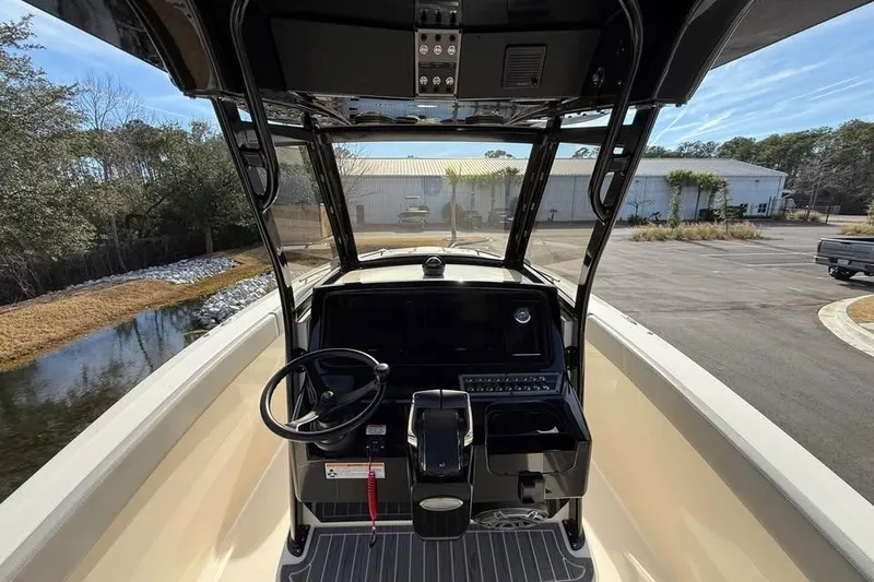 Slide: The Image of 2026 Scout 277 LXF boat helm with steering wheel and control panel, docked near water. - 10