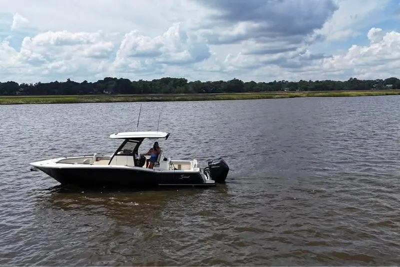 Slide: The Image of 2026 Scout 277 LXF boat cruising on a calm river under a cloudy sky. - 17