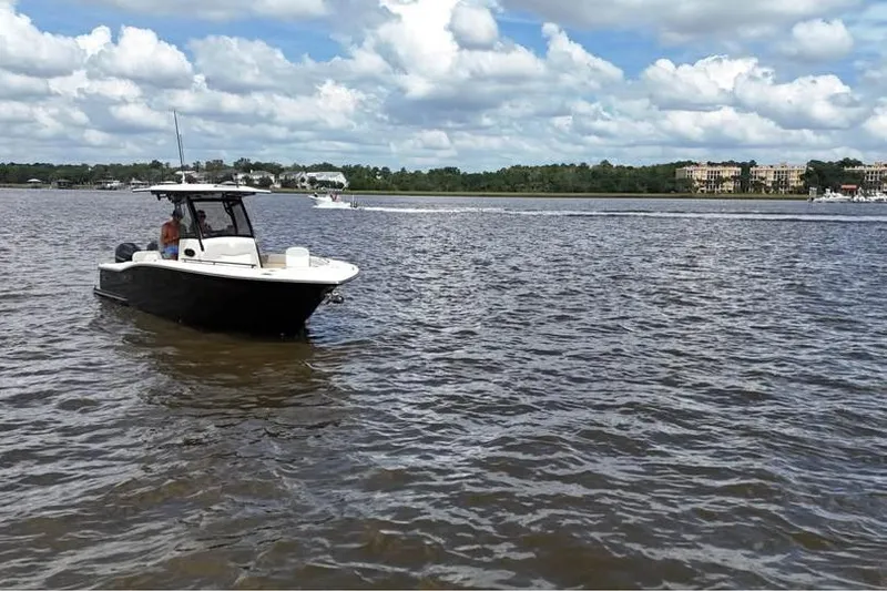 Slide: The Image of 2026 Scout 277 LXF boat on a calm river under a cloudy sky. - 20