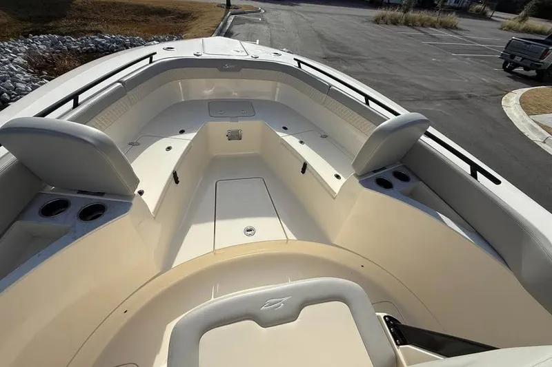 Slide: The Image of 2026 Scout 277 LXF boat interior with seating and cup holders in a parking lot. - 4