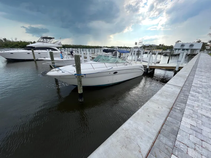 Slide: The Image of 2005 Sea Ray 290 Amberjack docked at a marina under a cloudy sky. - 1