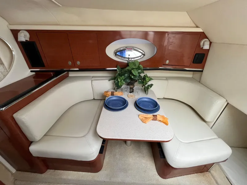 Slide: The Image of 2005 Sea Ray 290 Amberjack cabin dining area with table, seating, and porthole. - 11