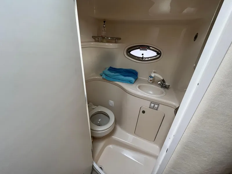 Slide: The Image of 2005 Sea Ray 290 Amberjack boat bathroom with toilet, sink, and porthole window. - 14