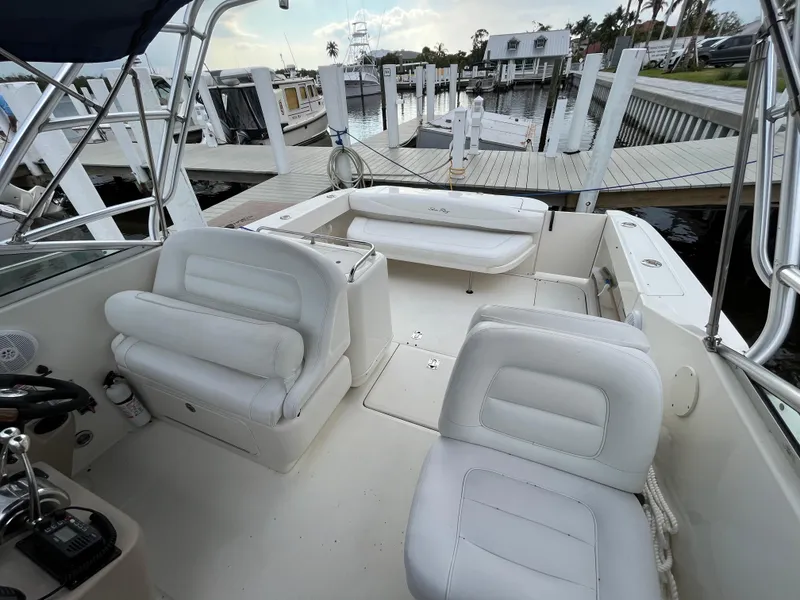 Slide: The Image of 2005 Sea Ray 290 Amberjack boat interior with white seating at a marina. - 7
