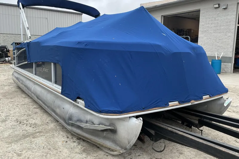 Slide: The Image of 2018 Berkshire 23RFC STS Fish pontoon boat covered with a blue tarp, parked outdoors. - 14