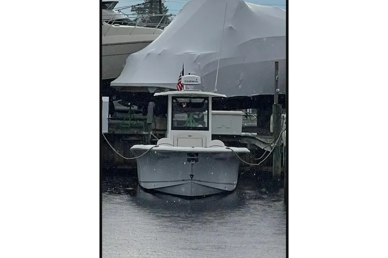 Slide: The Image of 2021 Sea Hunt Ultra 275 SE boat docked, front view, with covered vessel in background. - 10
