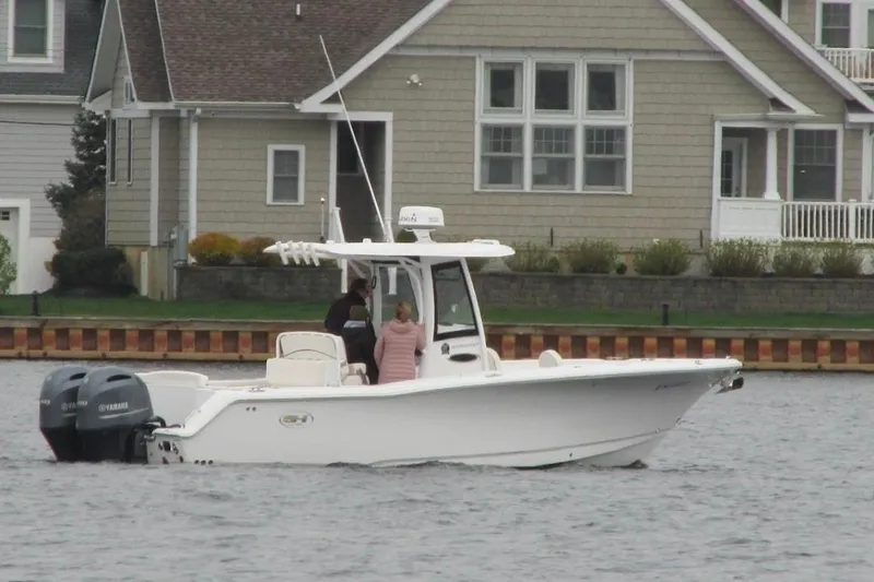 Slide: The Image of 2021 Sea Hunt Ultra 275 SE boat on water near residential area. - 2